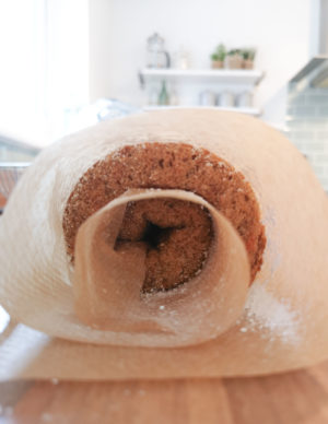 Carrot cake Swiss roll rolled up in baking paper