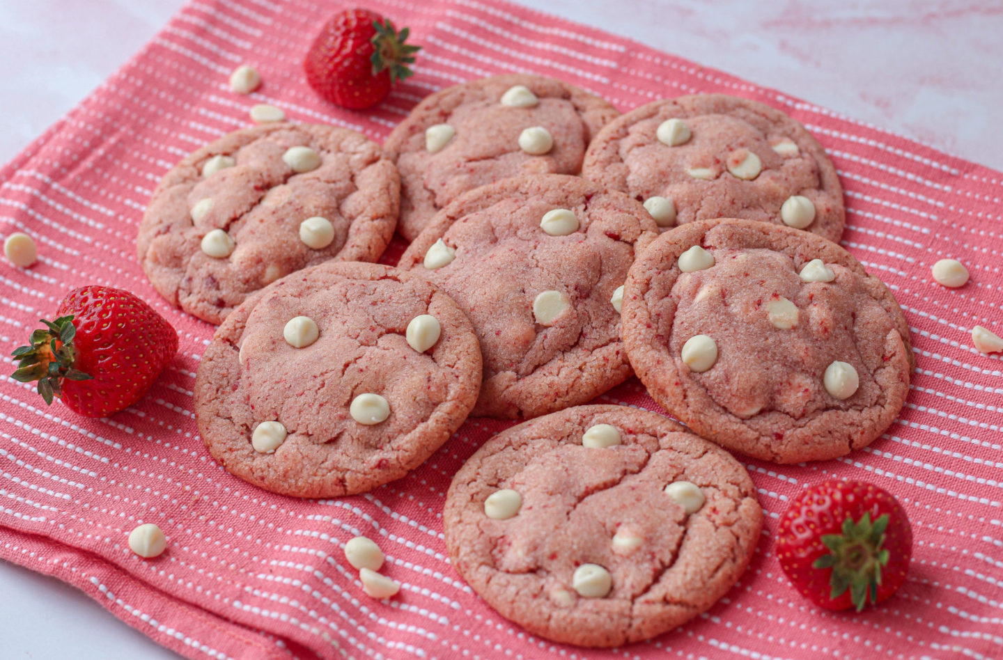 Several strawberry white chocolate cookies on a pink tea towel