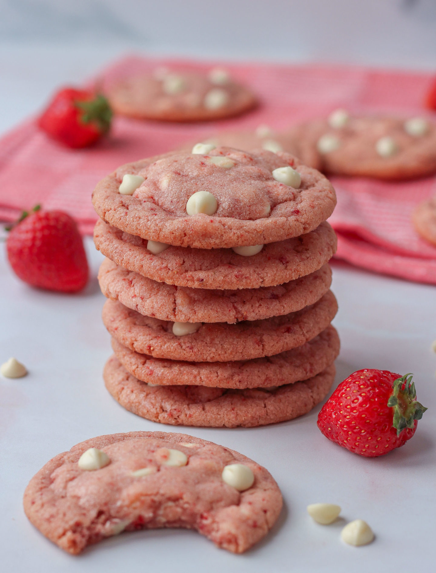 tower of chewy strawberry white chocolate cookies, with one in front with a bite taken out of it 