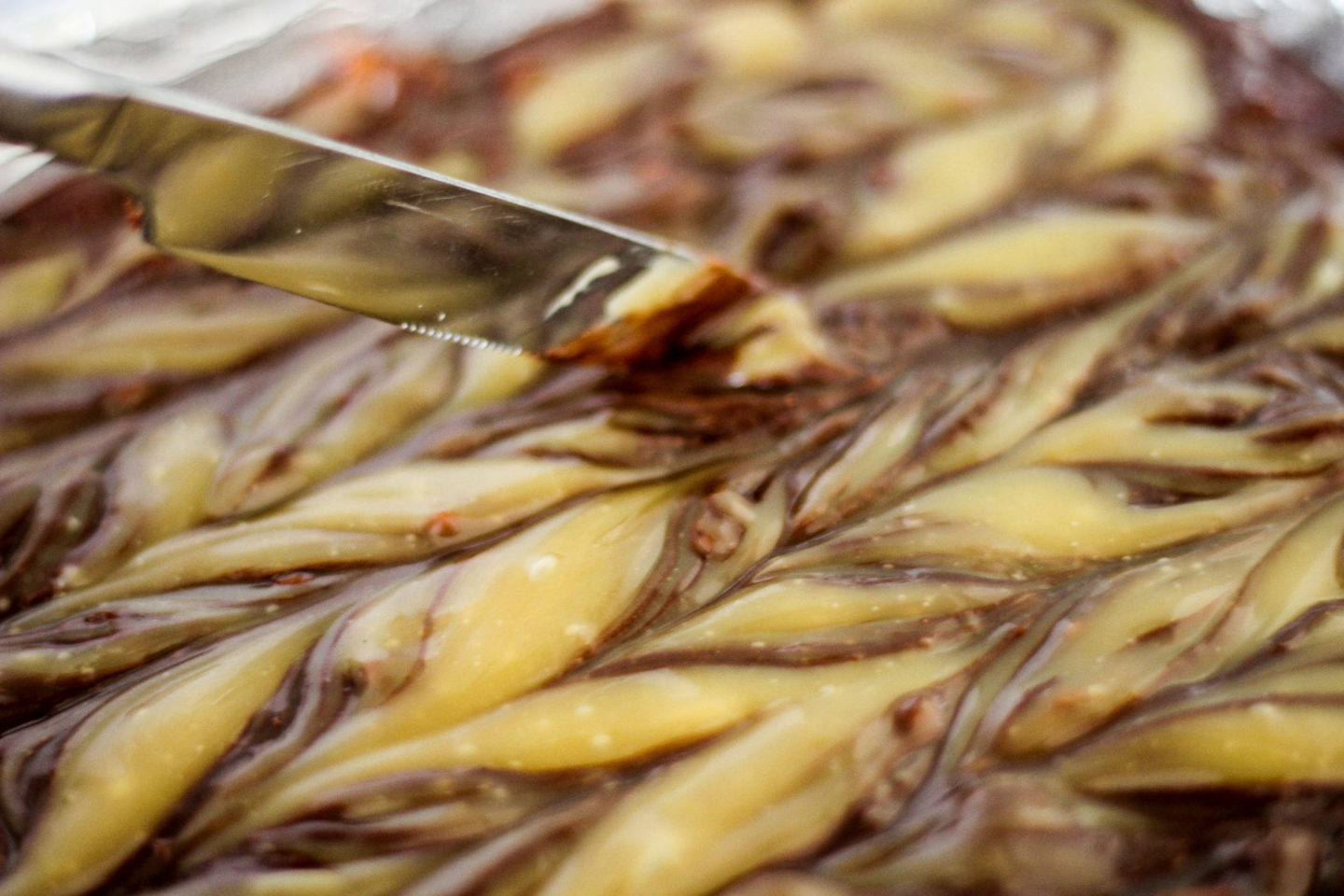 demonstrating how to swirl toffee sauce through brownie mixture