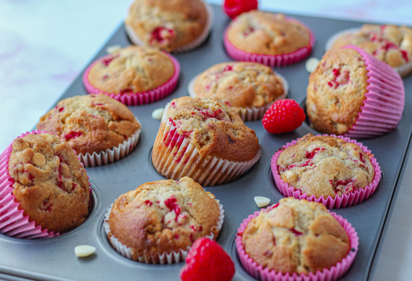 baked raspberry white chocolate muffins placed at different angles in a muffin tray
