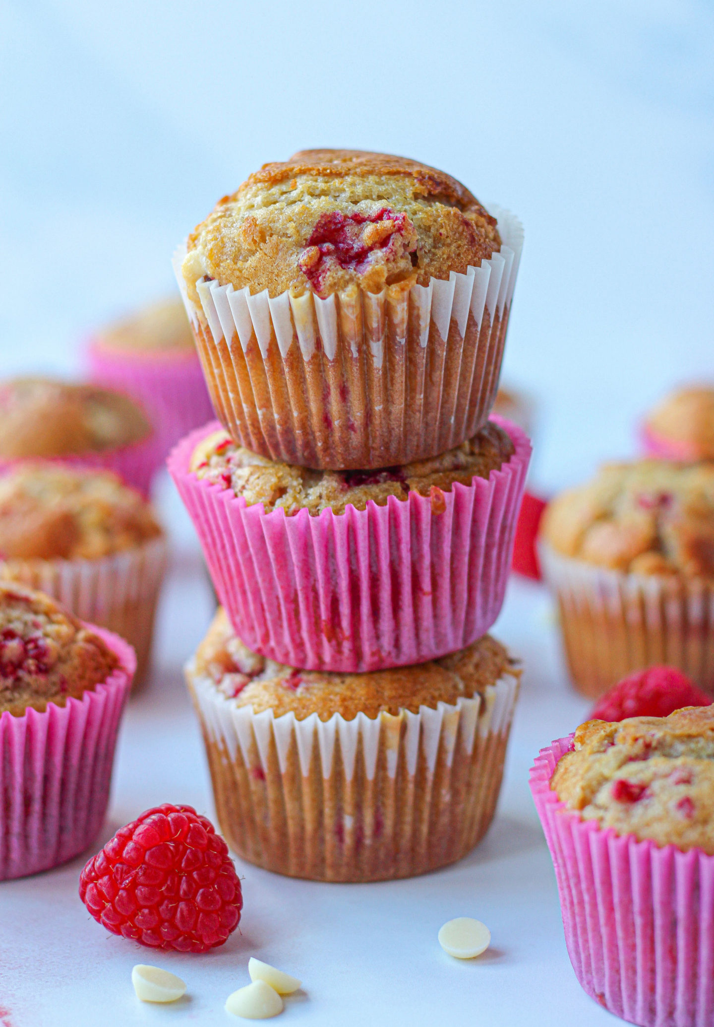 three raspberry white chocolate muffins stacked on top of each other 
