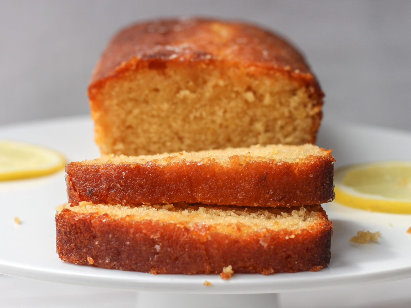 close up of slices of cake in front of lemon drizzle loaf cake