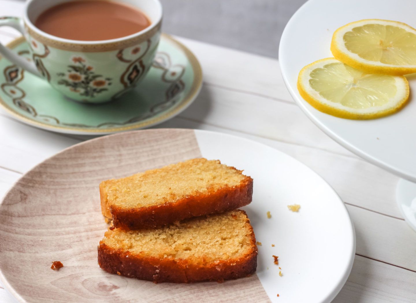 slices of lemon drizzle loaf cake with teacup and lemon slices