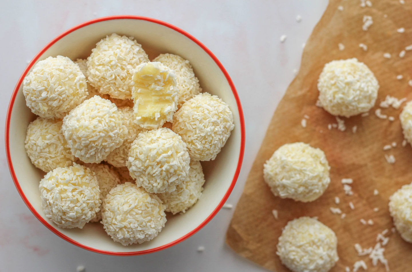 several white chocolate truffles in bowl with bite taken out of one