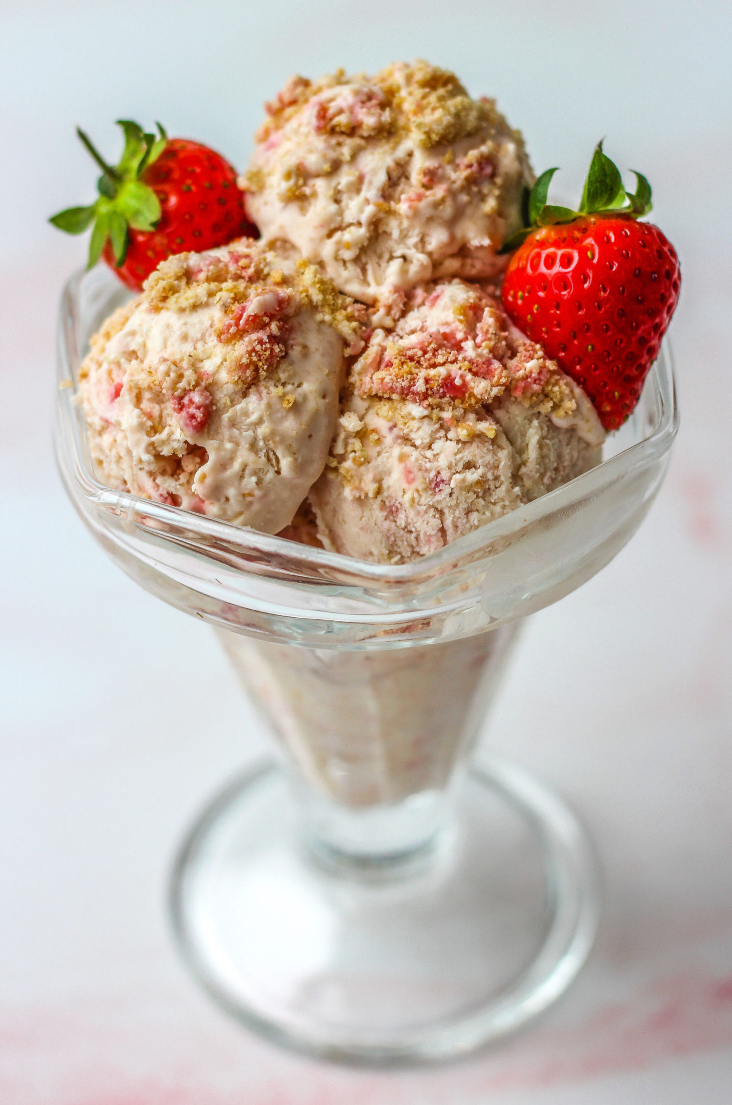 sundae dish filled with homemade no-churn ice cream and decorated with strawberries