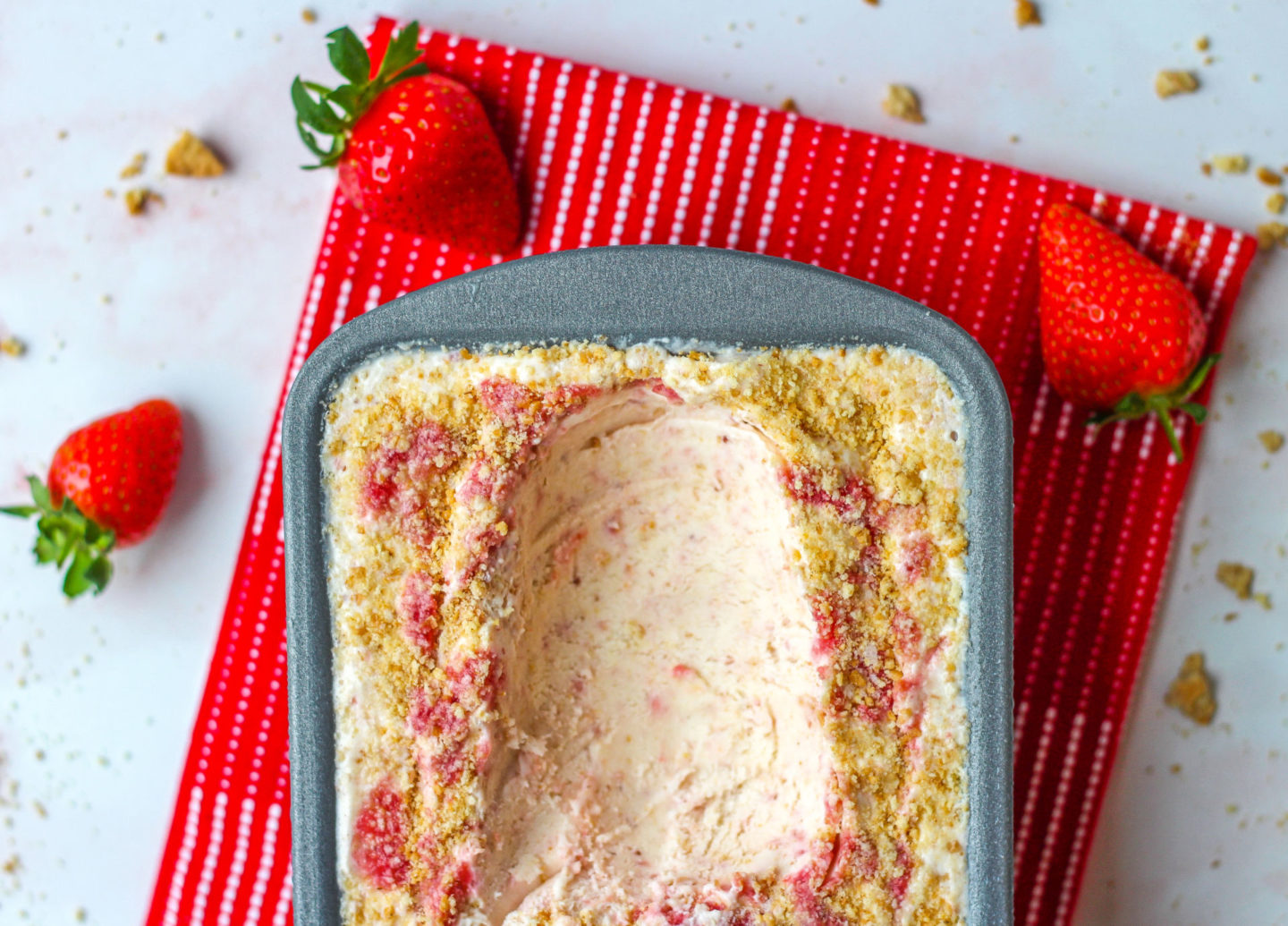 loaf tin  of strawberry cheesecake ice cream with scoop taken out of it