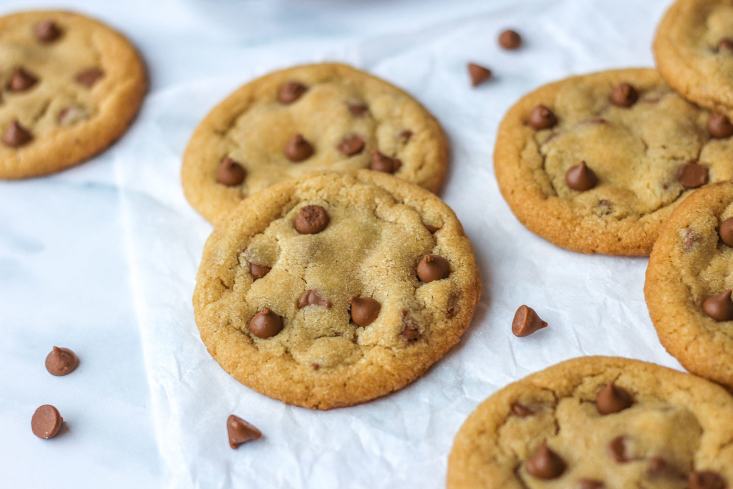 Several chewy chocolate chip cookies on parchment paper on a work surface