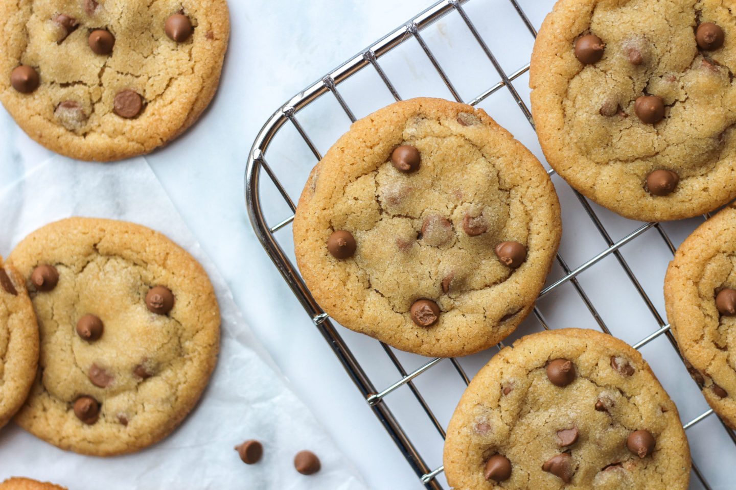 Several chewy chocolate chip cookies seen from above on counter top and wire rack.