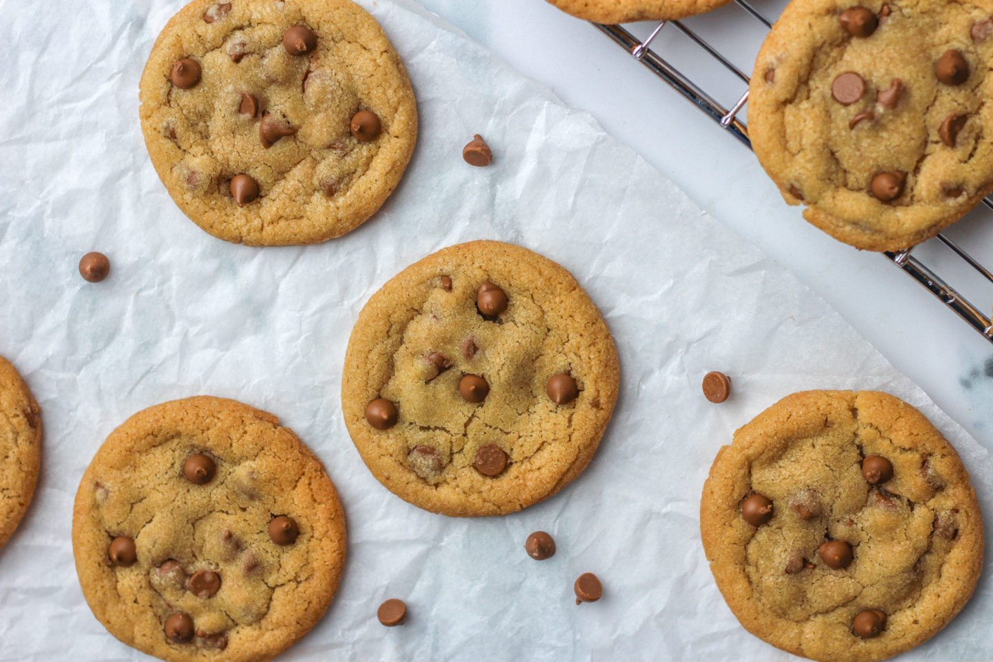 Several chewy chocolate chip cookies on parchment paper on a work surface