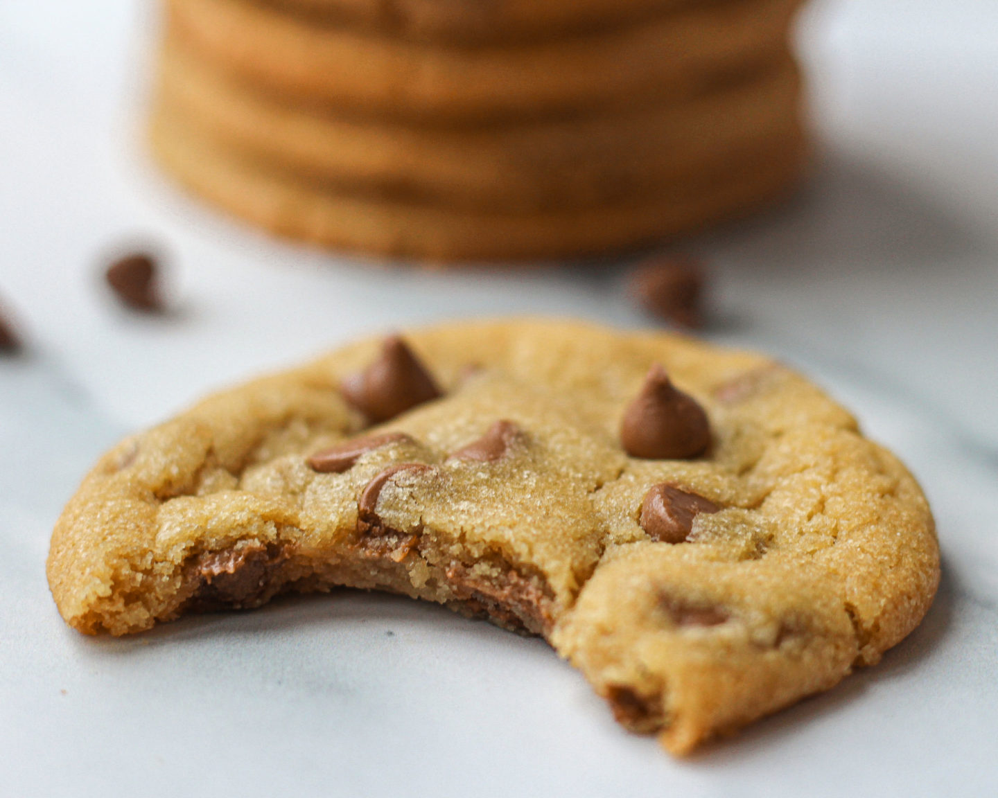 Close up of a chewy chocolate chip cookie with bite taken out of it, to show soft chewy centre.