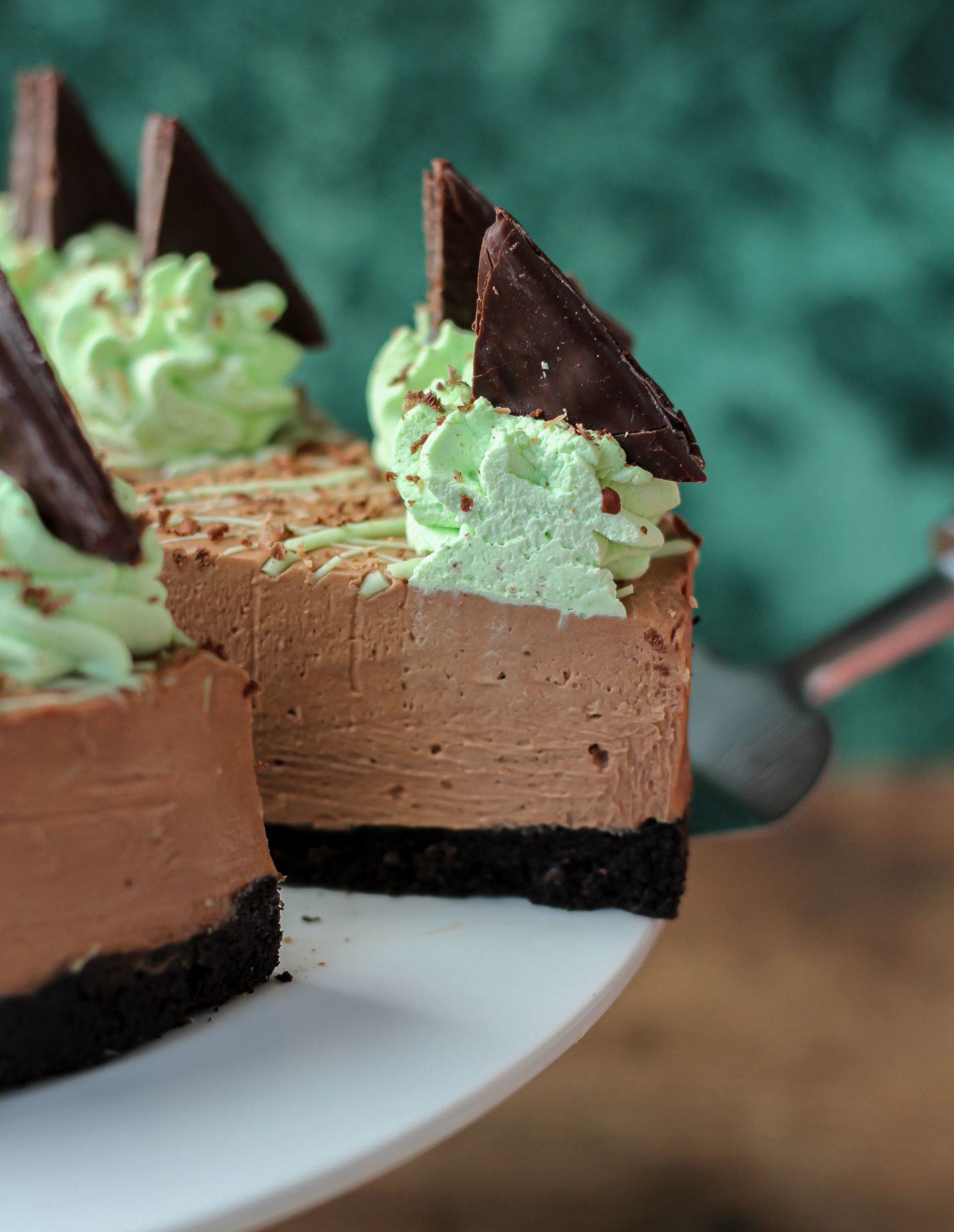 Close up of slice of no-bake mint chocolate cheesecake being removed from serving plate