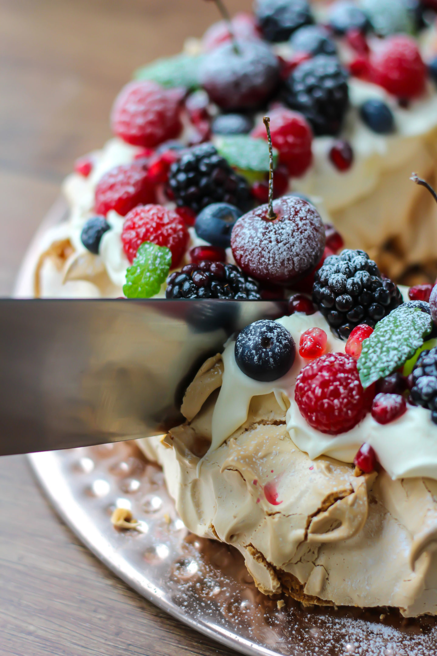 A knife cutting into the Christmas berry pavlova wreath