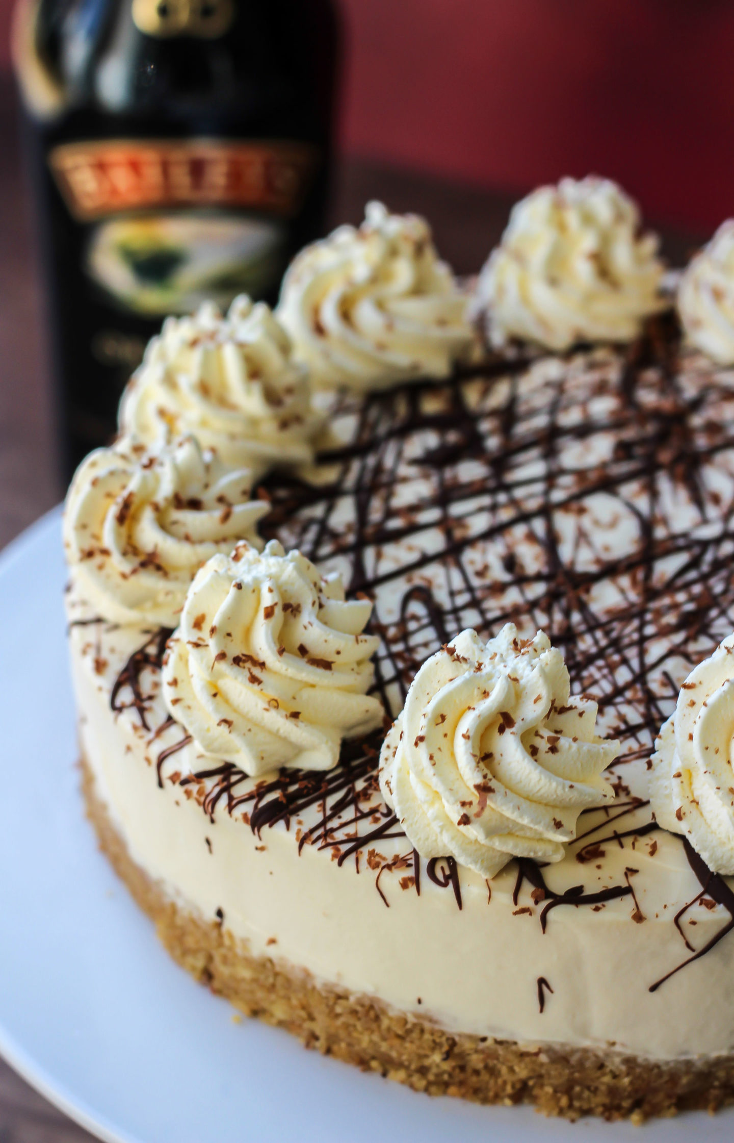 close up of no-bake Baileys cheesecake with bottle of Baileys in background