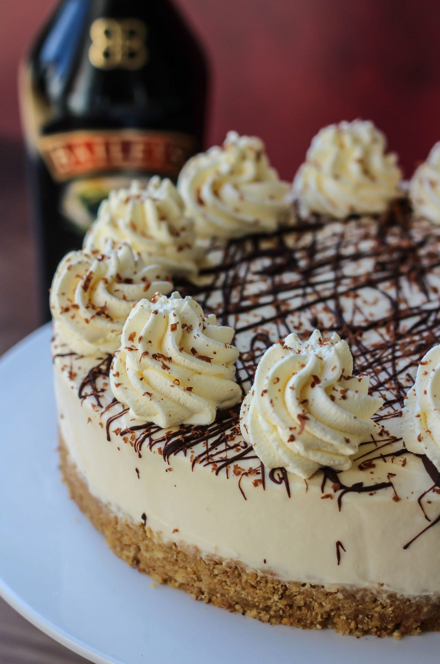 Close up of no-bake Baileys cheesecake with bottle of Baileys in the background