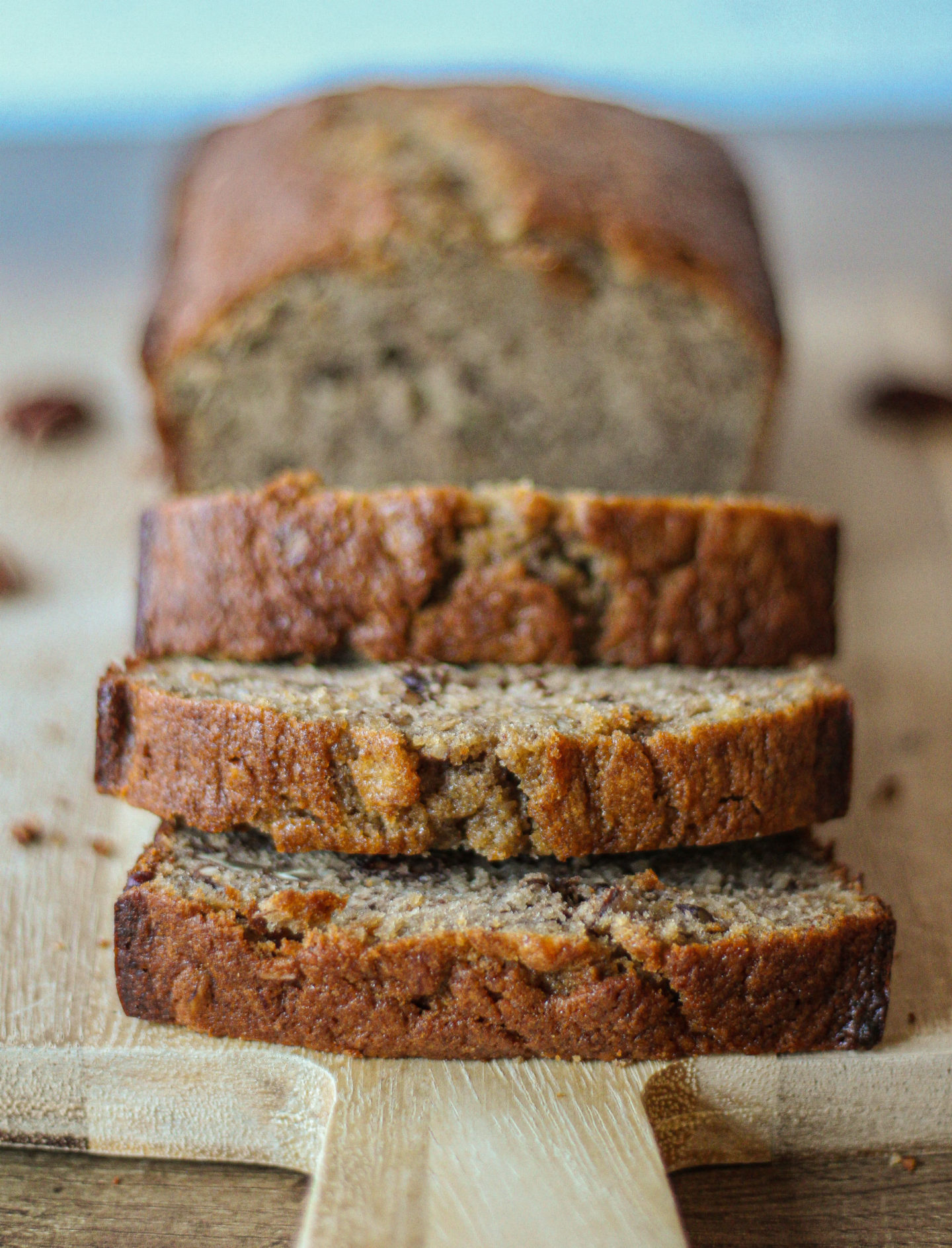 close up of stack of slices of banana loaf cake with loaf out of focus in background