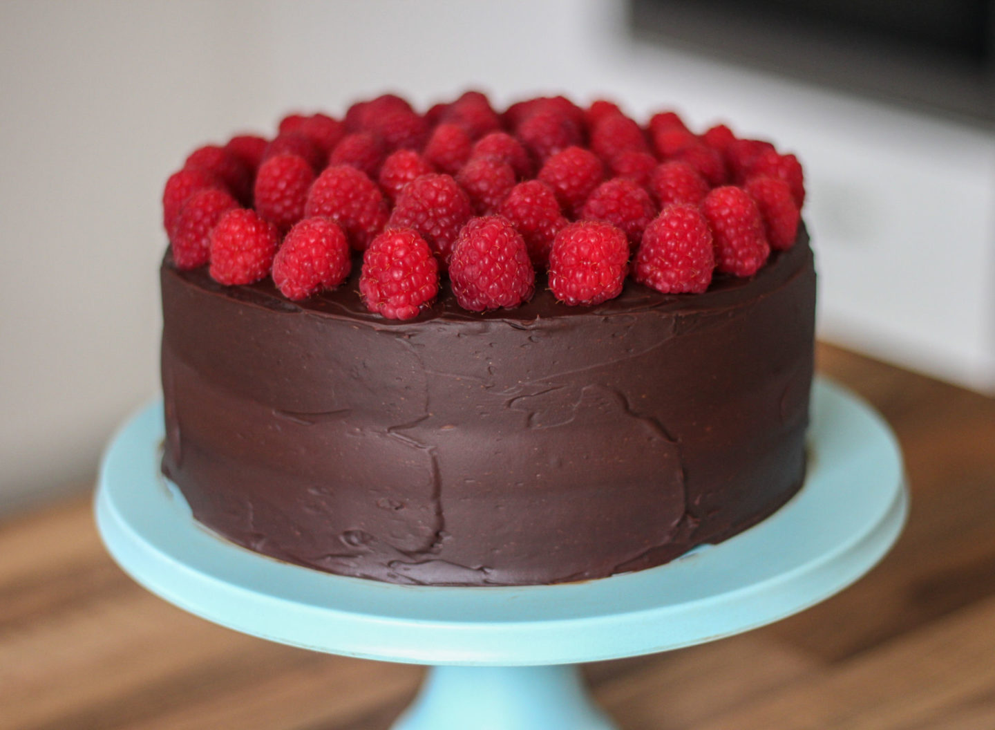 Whole unsliced signature chocolate cake on blue bamboo cake stand