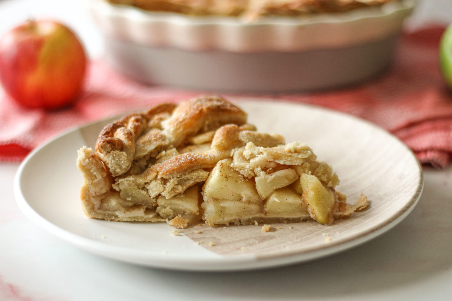 close up of slice of lattice apple pie with pie dish blurred in background
