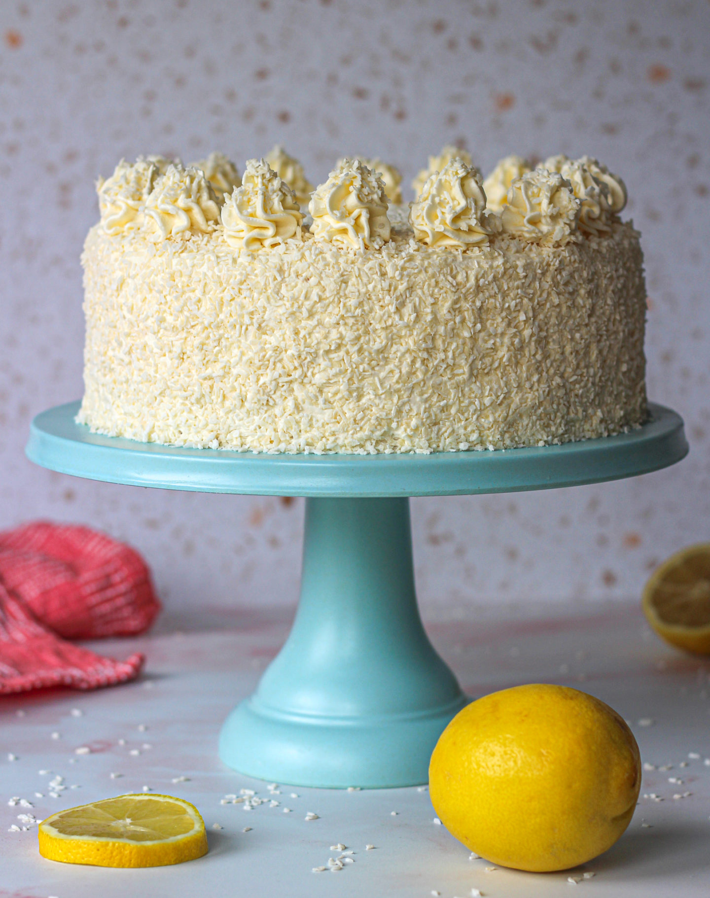 whole unsliced lemon coconut layer cake on blue cake stand