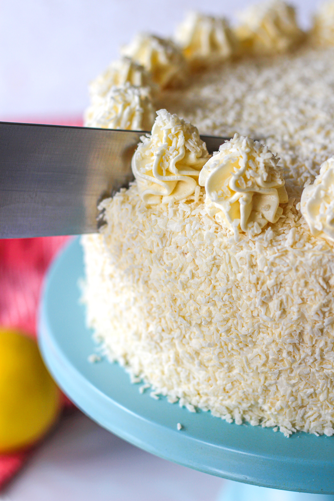 close up of a knife cutting into lemon coconut layer cake