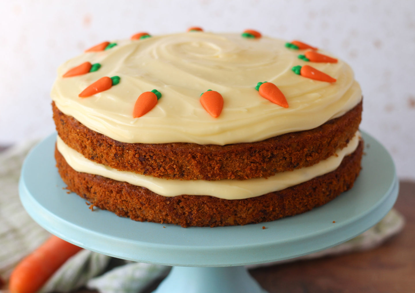 close up of a whole unsliced carrot cake on top of a blue cake stand