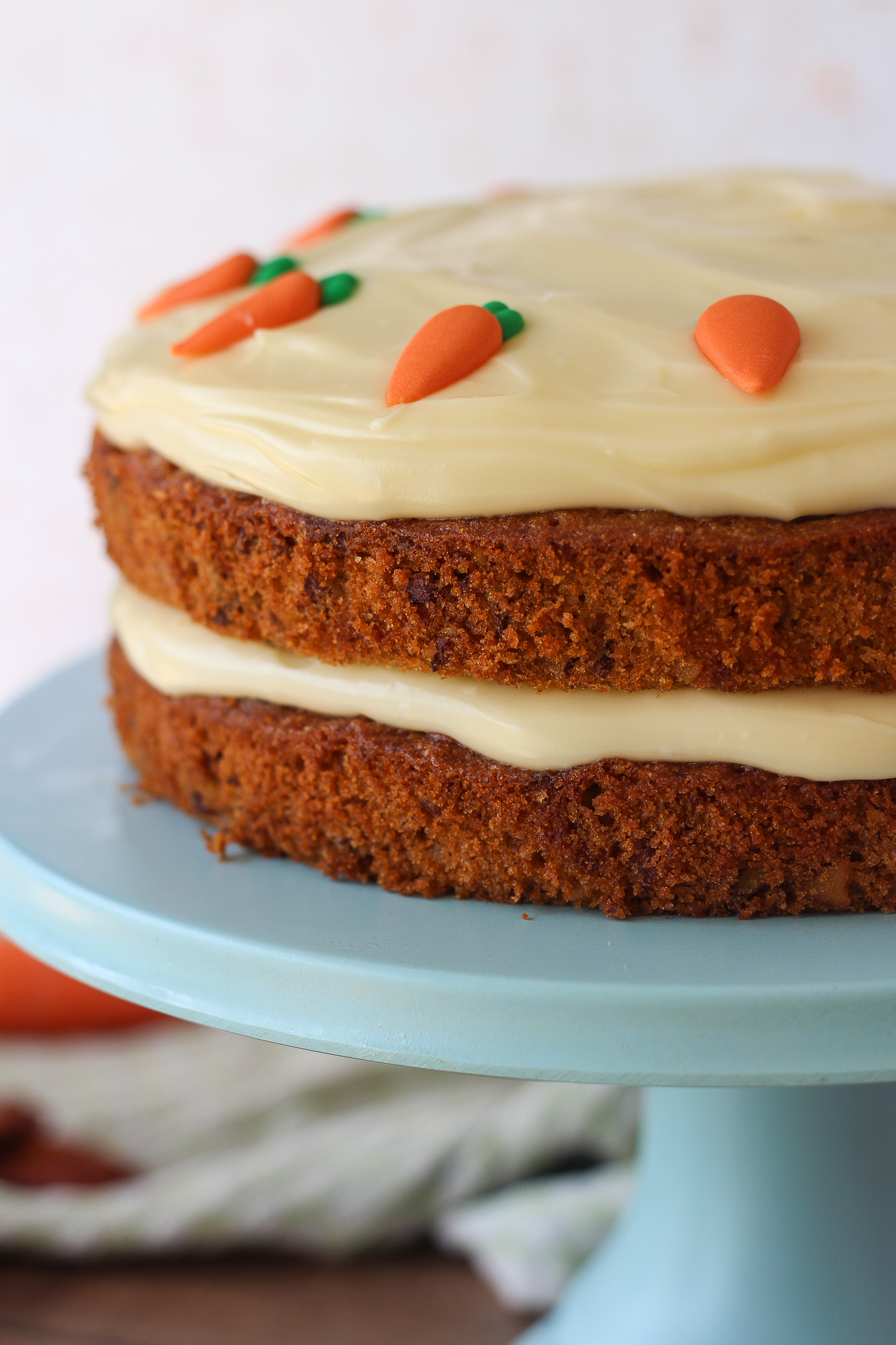 close up of unsliced carrot cake on blue cake stand